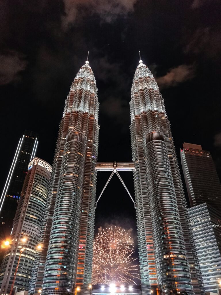 Stunning view of Petronas Twin Towers illuminated at night with breathtaking fireworks display in Kuala Lumpur.